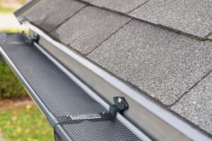 Plastic safety net over new dark gray plastic gutter on asphalt shingle roof