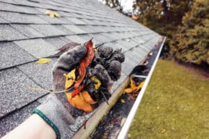 Cleaning leaves and debris from gutters in the fall