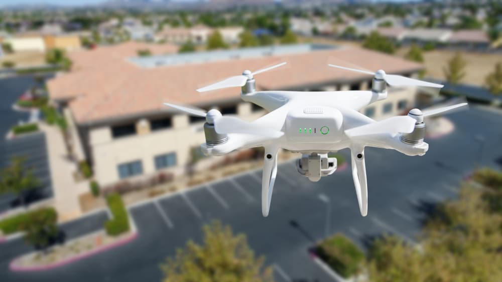 Unmanned aircraft system quadcopter drone in the air near a corporate industrial building