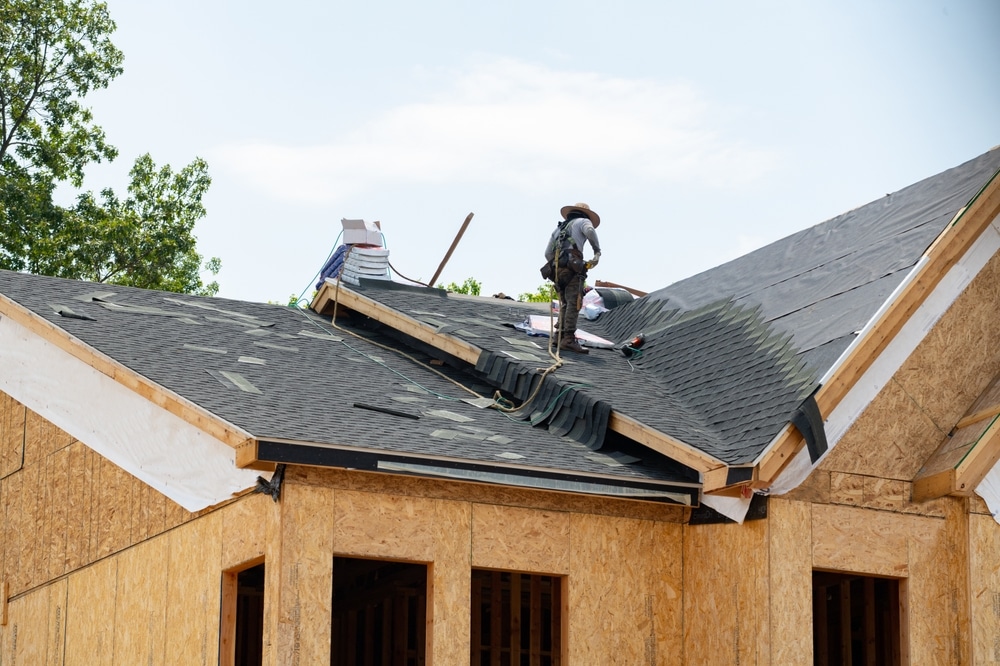 Worker installs asphalt roofing shingles