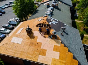 Builders installing new shingles while repairing the roof of a house