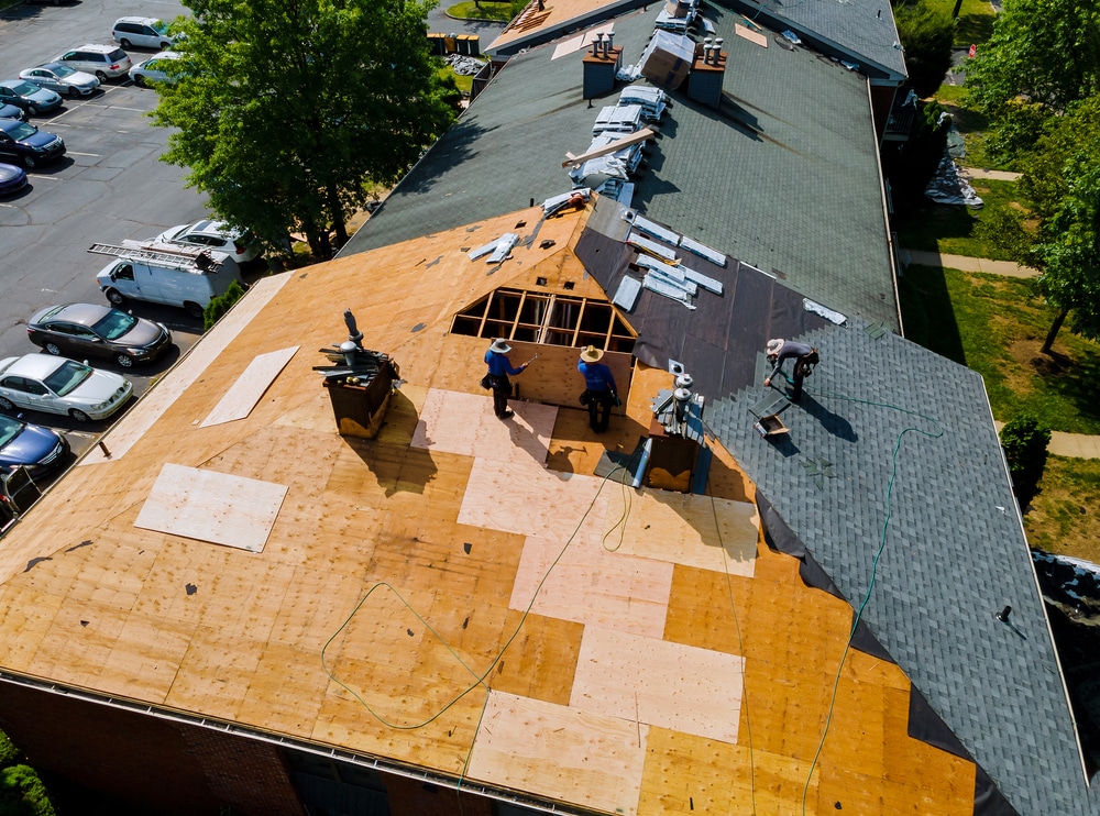 Builders installing new shingles while repairing the roof of a house