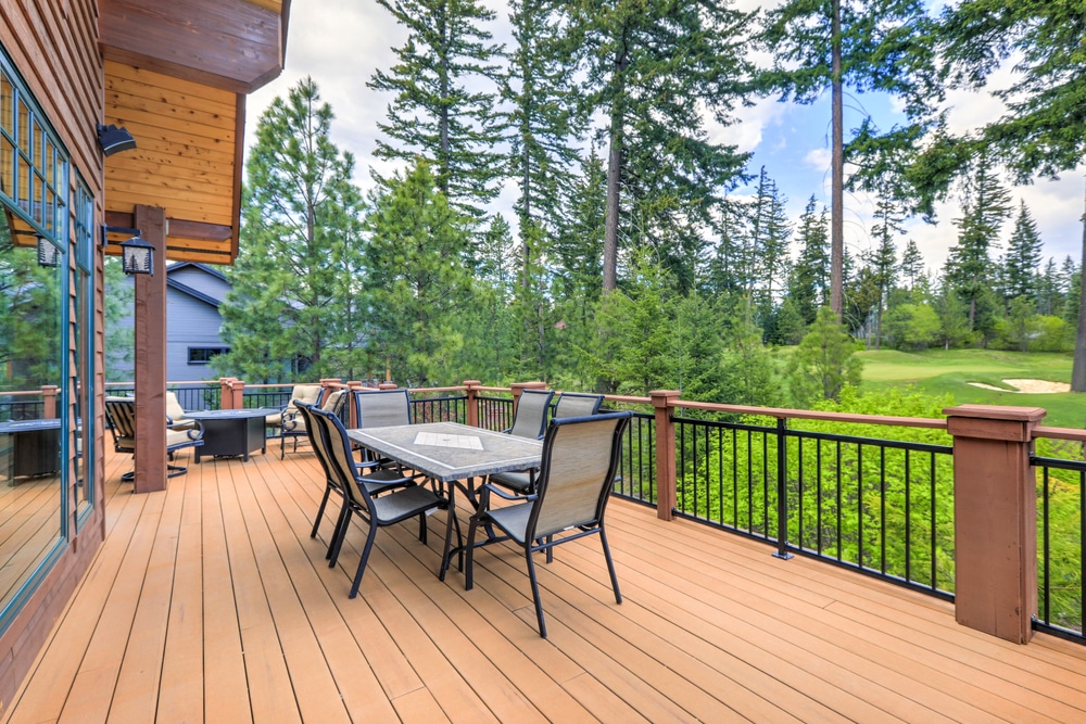 Beautiful large cabin house with large wooden deck, chairs and table overlooking the golf course