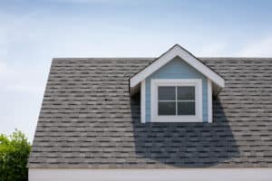 Roof shingles with attic house on top of house among many trees