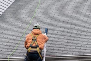 A man walking on roof shingles and ladder during roof inspection