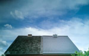 Half cleaned metal roof of a house showing the effect before and after roof cleaning