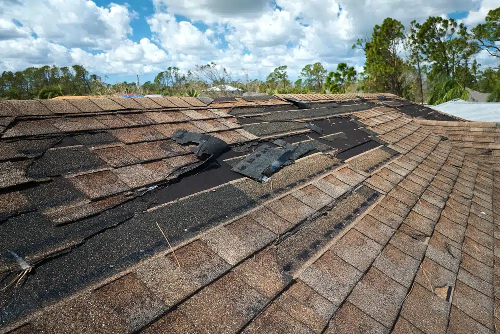 Damaged house roof with missing shingles after a hurricane.
