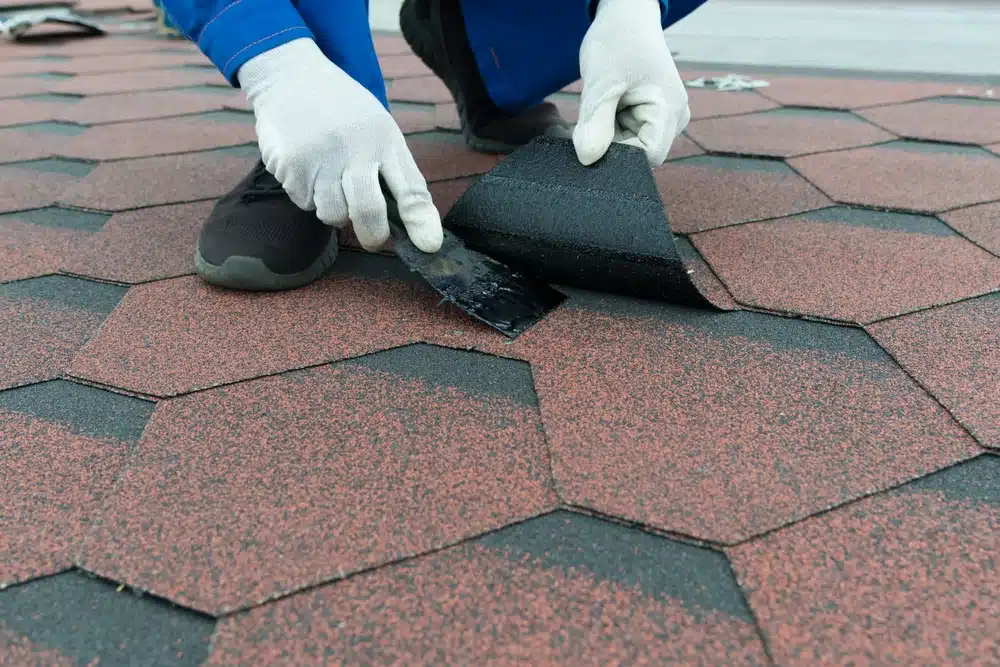 A worker applying black mastic with a spatula
