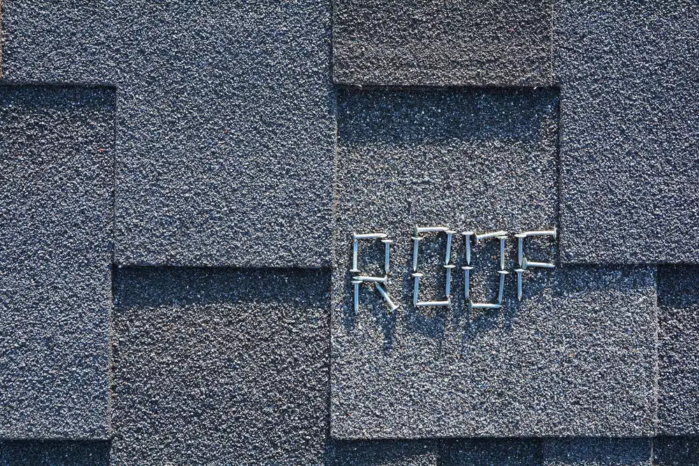 Close-up of asphalt roofing shingles and nails background.
