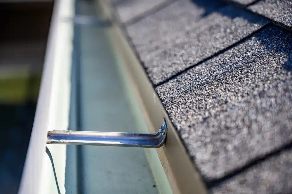 View inside roof gutter with clips and edge of shingles
