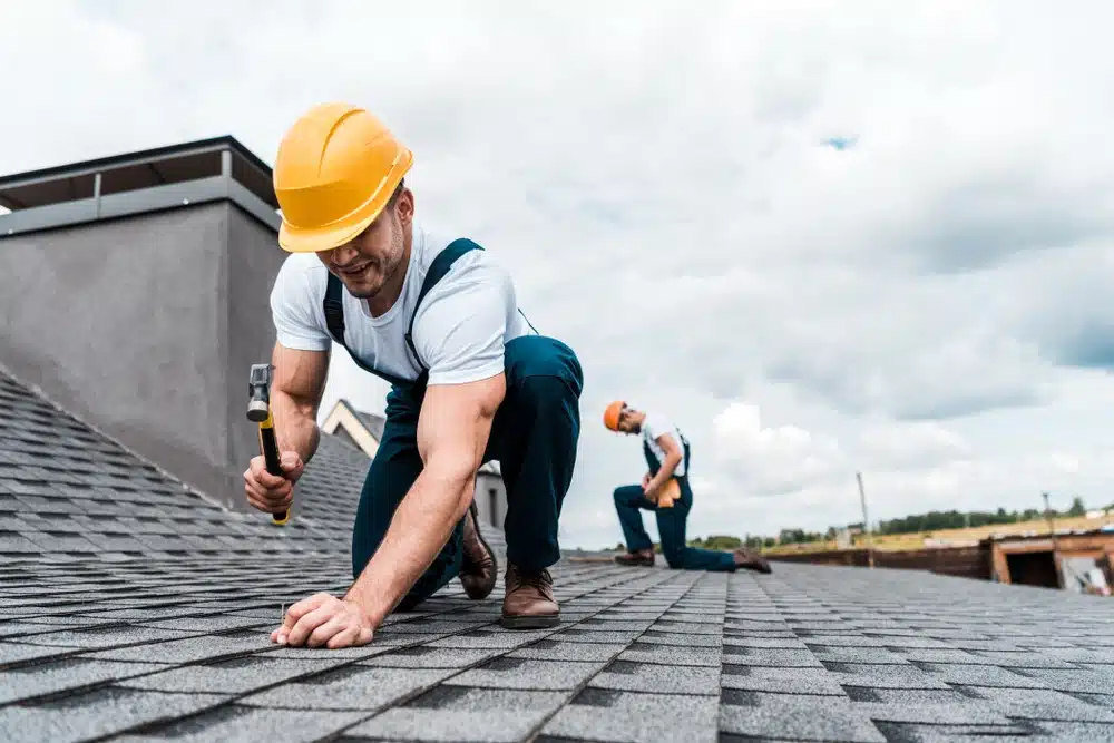 Handyman holding hammer while repairing roof
