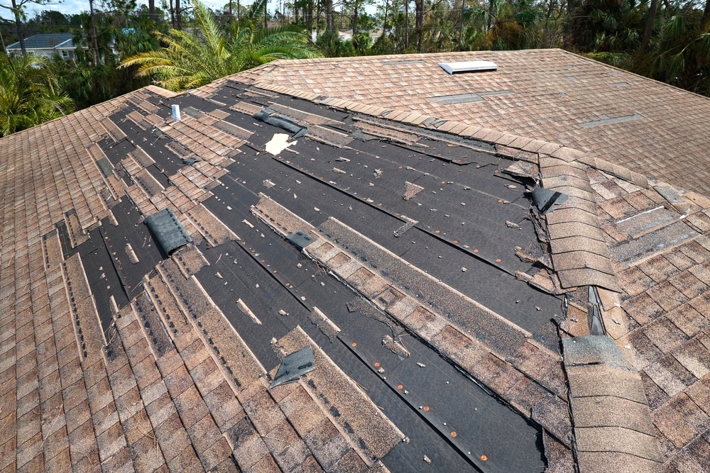 Damaged house roof with missing shingles
