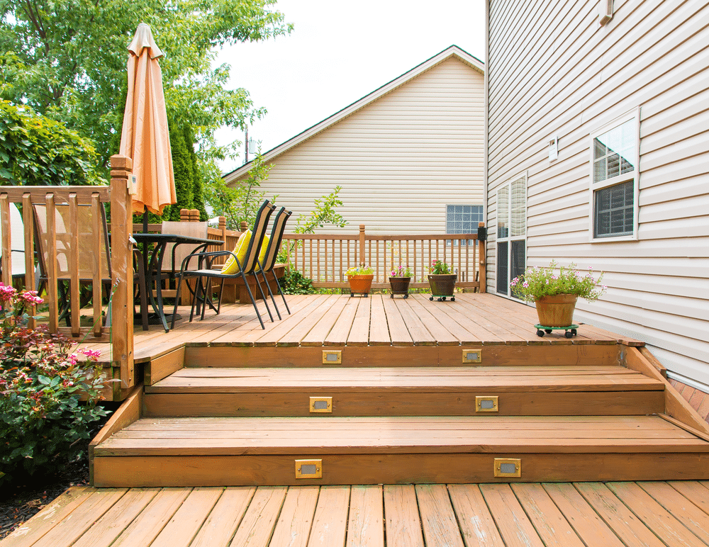 Large wooden walkout deck with flat roof extension