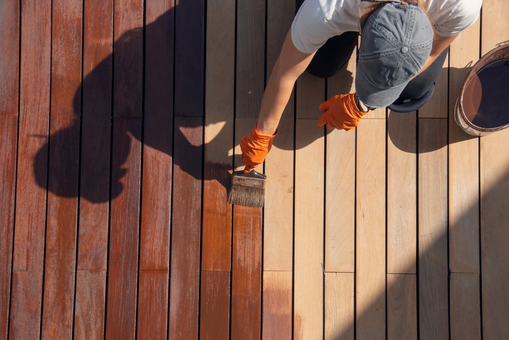 Homeowner maintaining a wooden deck