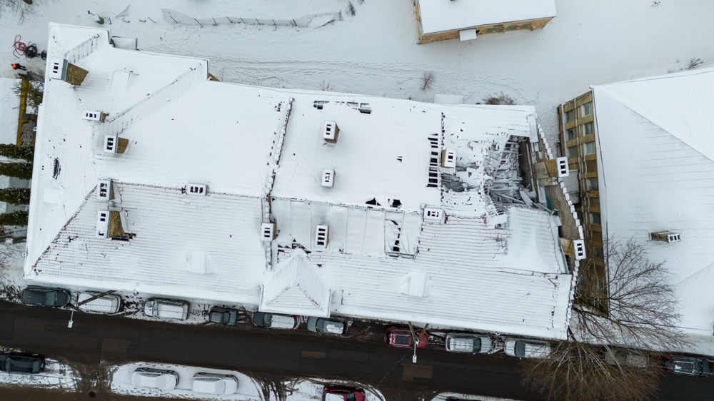 Drone photography - a top view of a building with broken rooftop needs replacement during winter day
