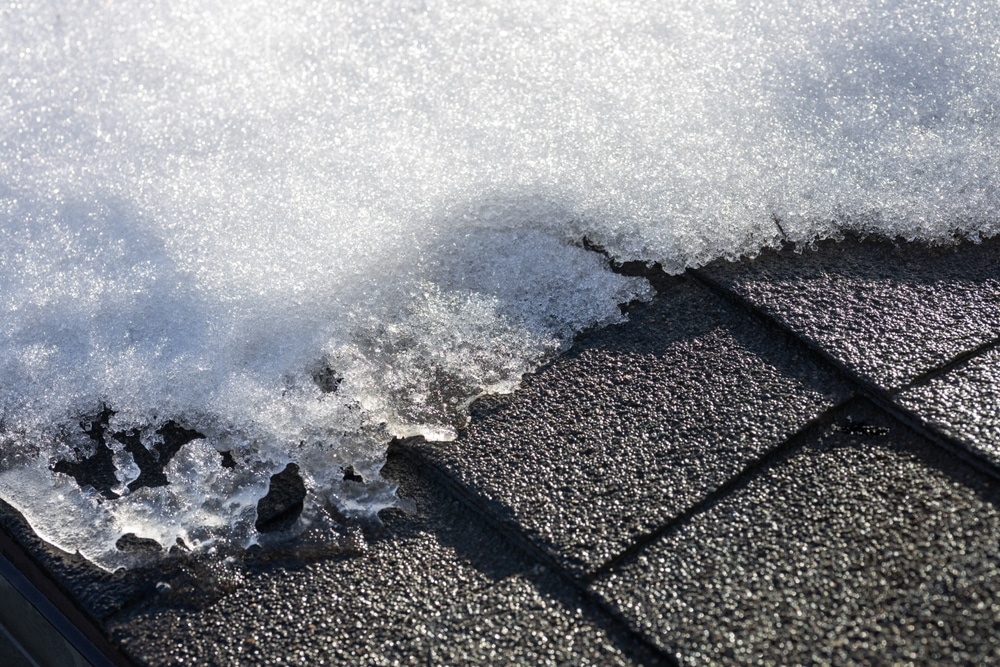 Abstract texture background of white snow beginning to melt slightly on an asphalt shingle roof, on a sunny winter day