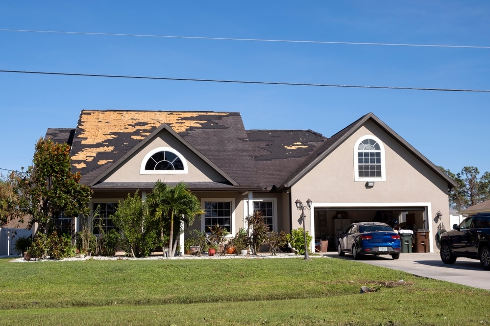 Damaged house roof with missing shingles after hurricane Ian in Florida, consequences of natural disaster
