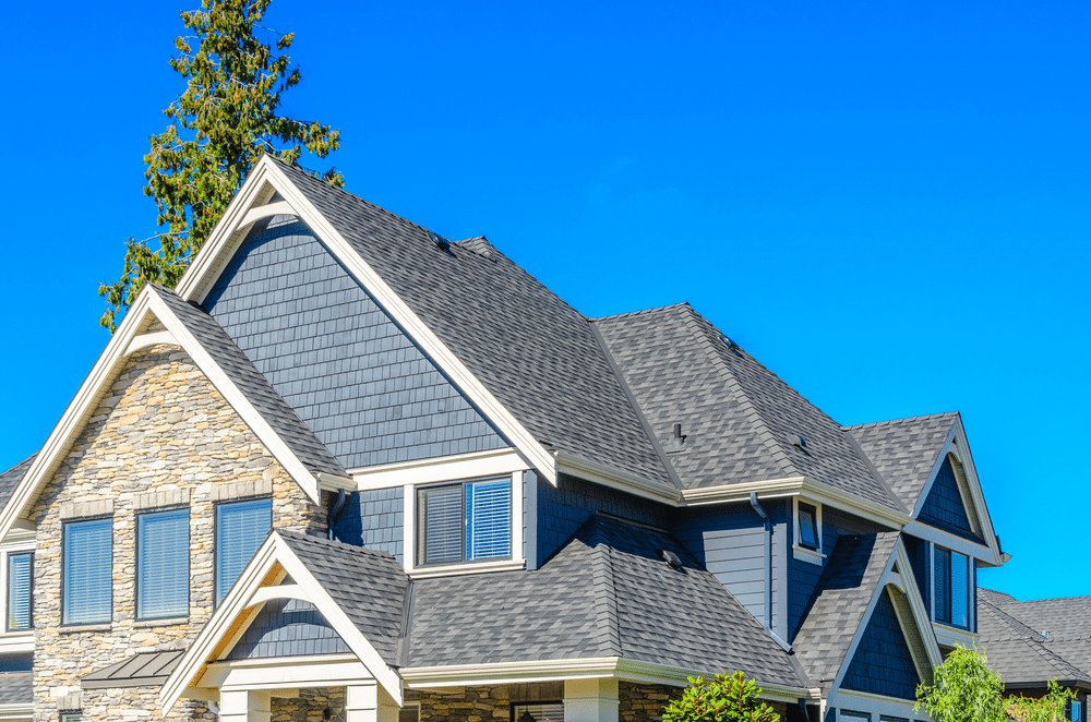 An isolated house featuring a modern design with a large, gray-colored roofing material, surrounded by open land.
