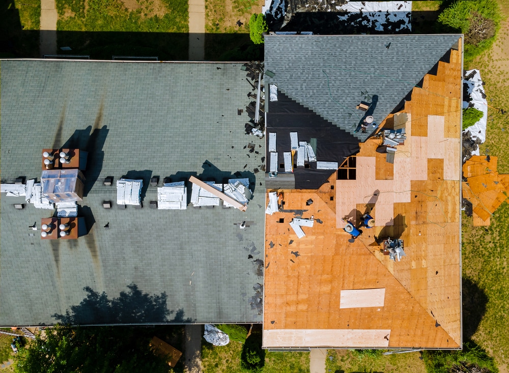 Aerial view of roof construction repairman on a residential apartment with new roof shingle being applied
