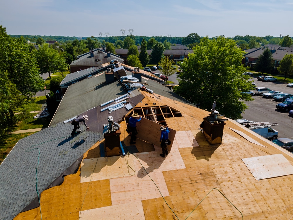 Workers replacing old gray asphalt shingles with new ones on a roof, enhancing the home's durability and curb appeal
