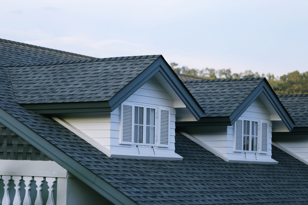 Close-up of a shingle-roofed house garret with a blurred sky in the background.
