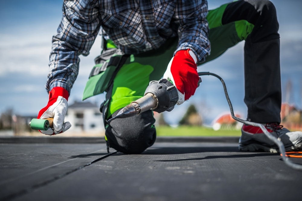 Worker installs EPDM membrane using hot air blower
