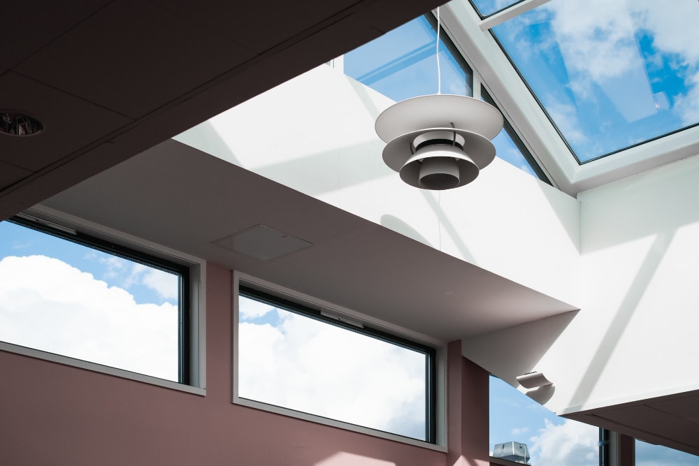 Low angle shot of a lamp hanging inside a building with a glass ceiling, skylight on the rooftop, natural light