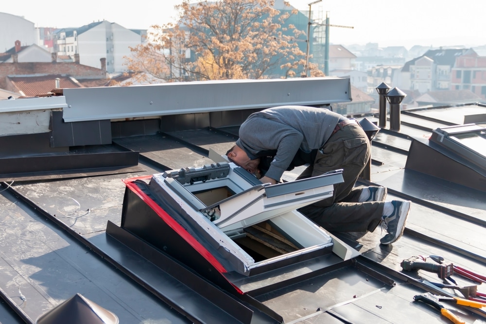 A roofer and window master work. The craftsman covers the skylight with sheet metal. skylight installation on new roof