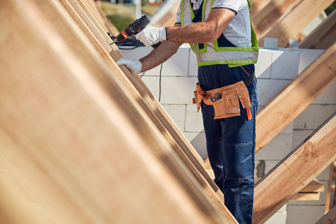 Roofing workers are diligently applying underlayment to the roof, ensuring that layers are properly installed for protection