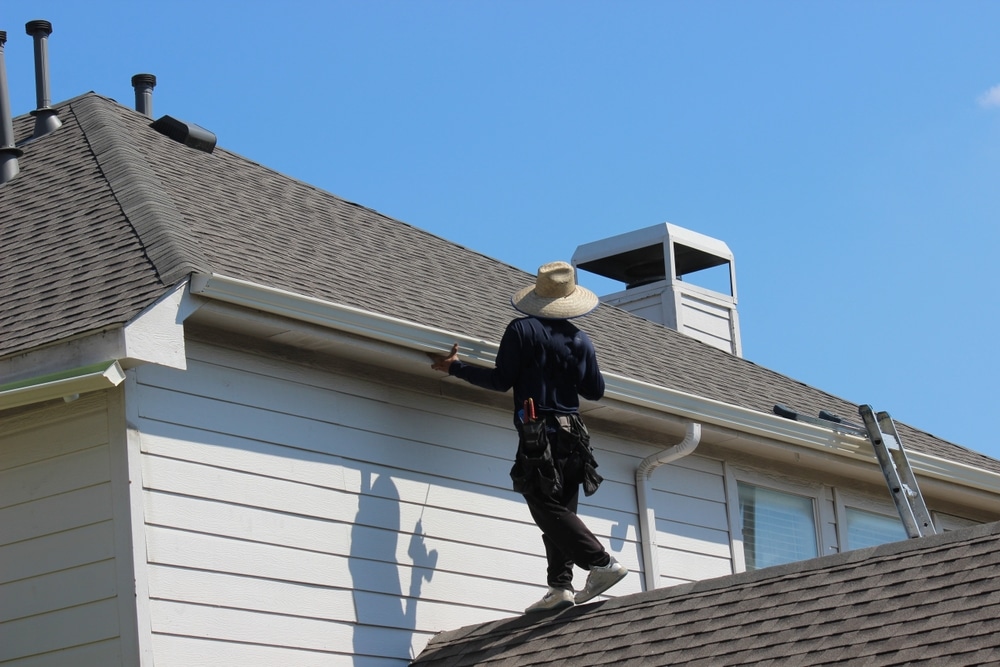 Roofing, gutter installation contractor installing new roof gutters in a residential house in North Texas
