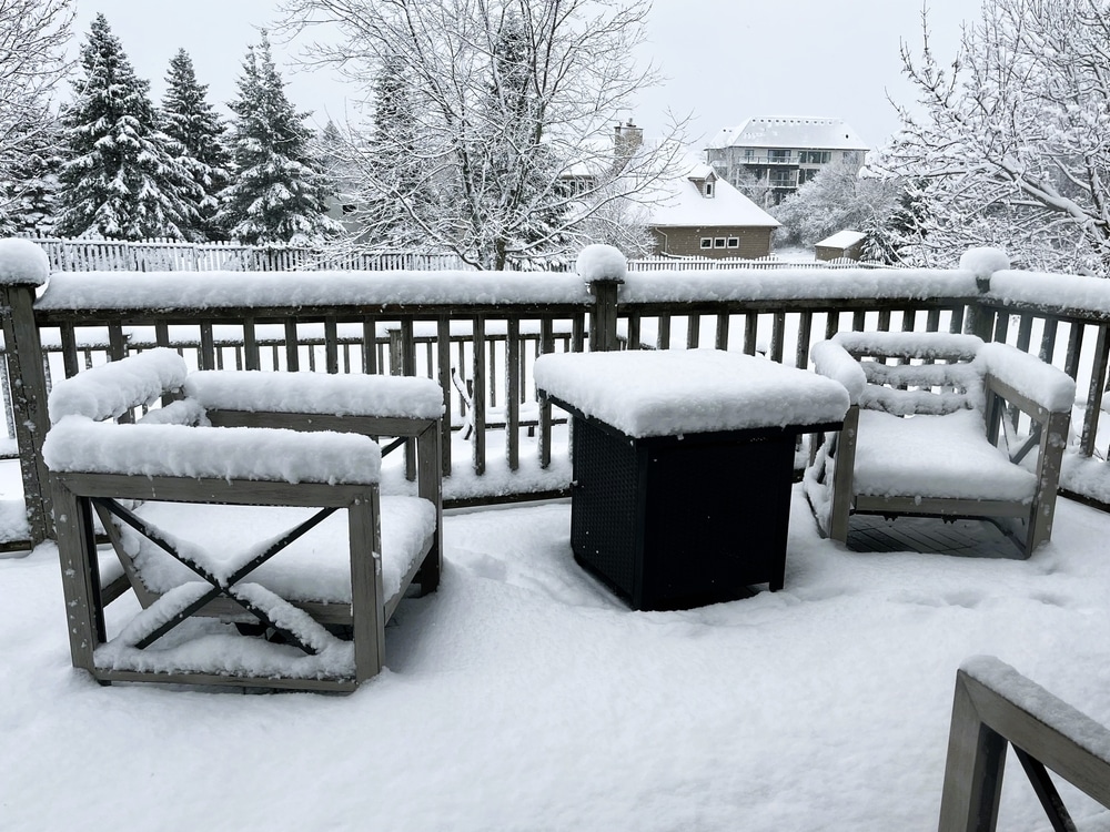 Fresh white snow builds up on the patio furniture on a back yard porch signaling the start of winter.