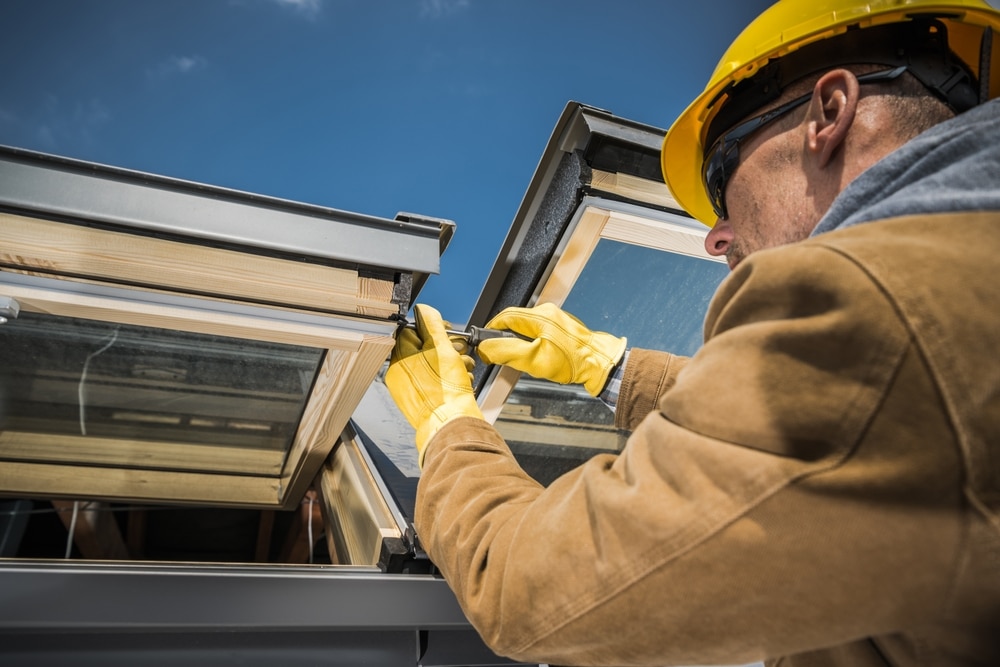 Caucasian Worker Wearing Safety Helmet and Protective Gloves Carrying Out Repair Works on Roof Skylight Windows