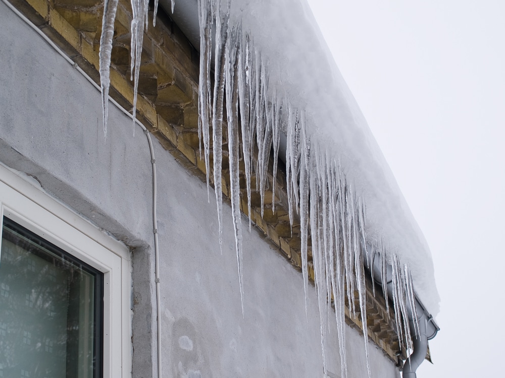 Icicles on a roof winter background image, ice dams on the rooftop and gutters, winter snow ice