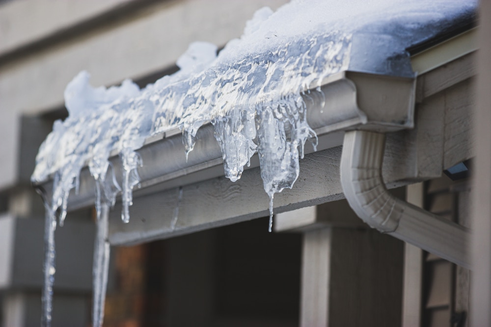 Close up captured picture of Icicles hanging from frozen ice filled gutter, frozen gutter causing potential damage