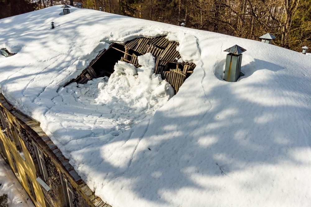 Broken roof shingles under the weight of fallen snow on an old building - a picture taken from a drone