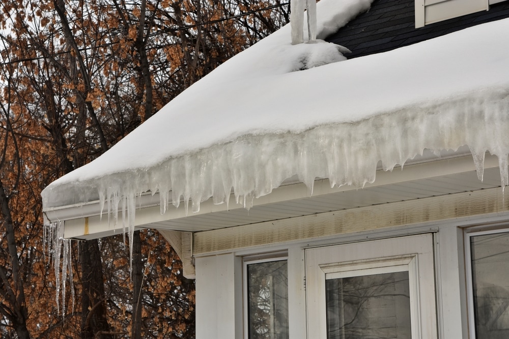 Melting snow on roof creating ice dam in gutter with possible water damage inside and outside