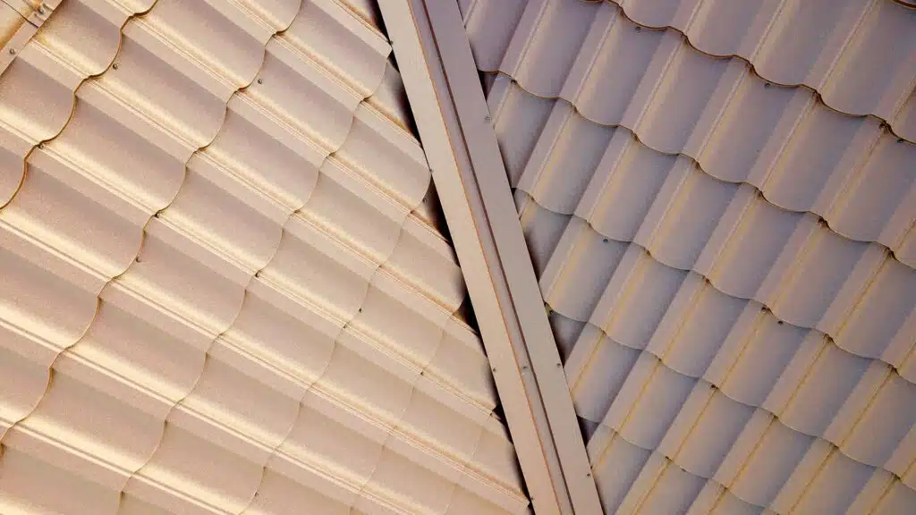 House roof surface covered with brown metal tile sheets, beige and white metal roofing material, roof repair in Boston