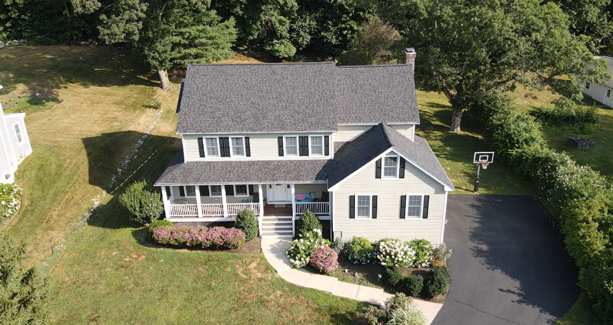 A newly installed dark asphalt shingle roof on a two-story suburban home, showcasing a roof installation in Boston MA