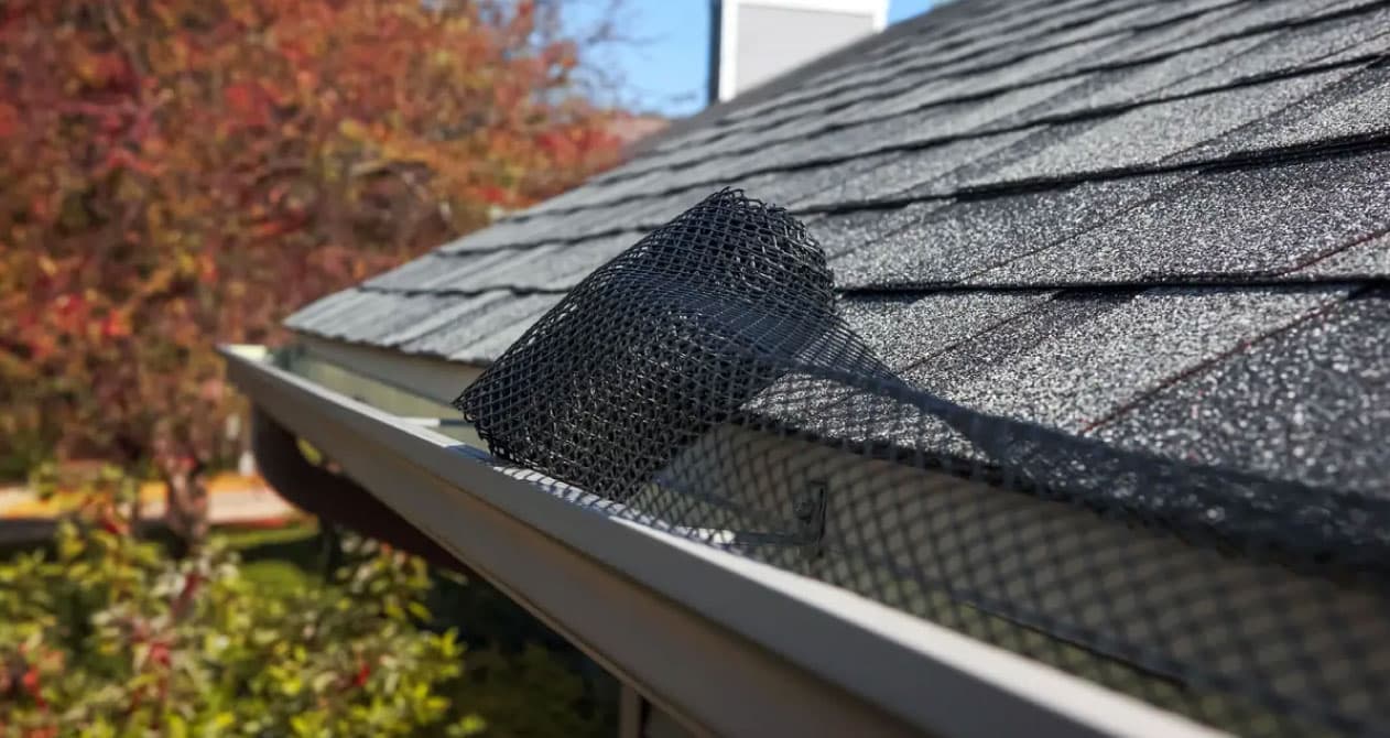 A black mesh gutter guard is partially installed on the roof for debris protection, showing a gutter replacement in Boston MA