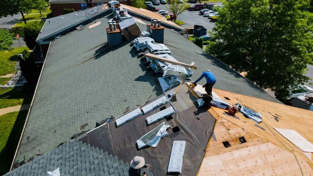 Construction workers installing new shingles on a residential roof during a roof installation, roof replacement, roof repair