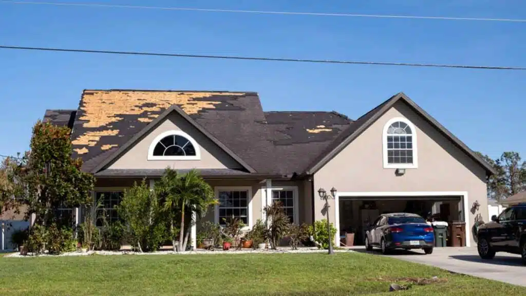 Damaged house roof with missing shingles after hurricane Ian in Florida, consequences of natural disaster