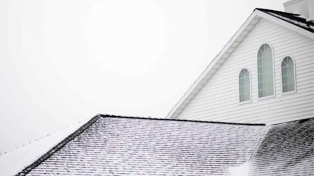 Snow-covered church roof with a steeple, highlighting winter roof maintenance, ice buildup prevention, and insulation