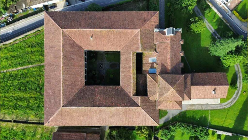 Aerial view of the Santa Clara Monastery with a traditional terracotta-tiled roof, surrounded by greenery.