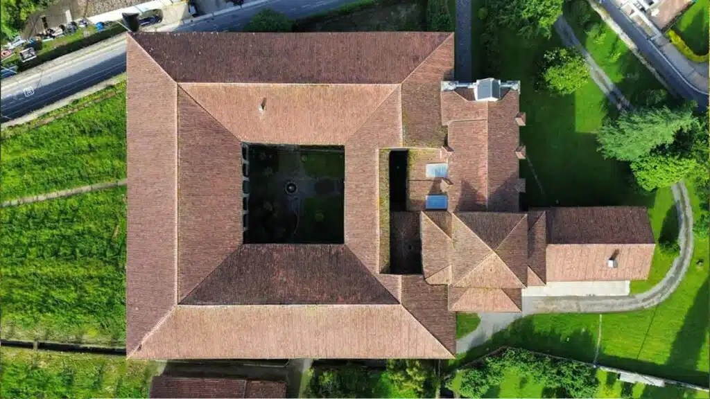 Aerial view of the Santa Clara Monastery with a traditional terracotta-tiled roof, surrounded by greenery.