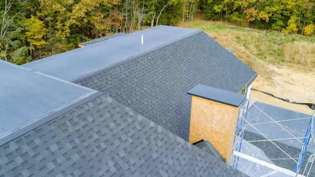 Aerial view of a newly built house featuring an asphalt shingle roof, surrounded by a natural landscape.