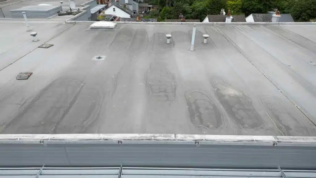 Aerial view of a flat roof with visible wear and tear, potential signs of hidden roof water damage.