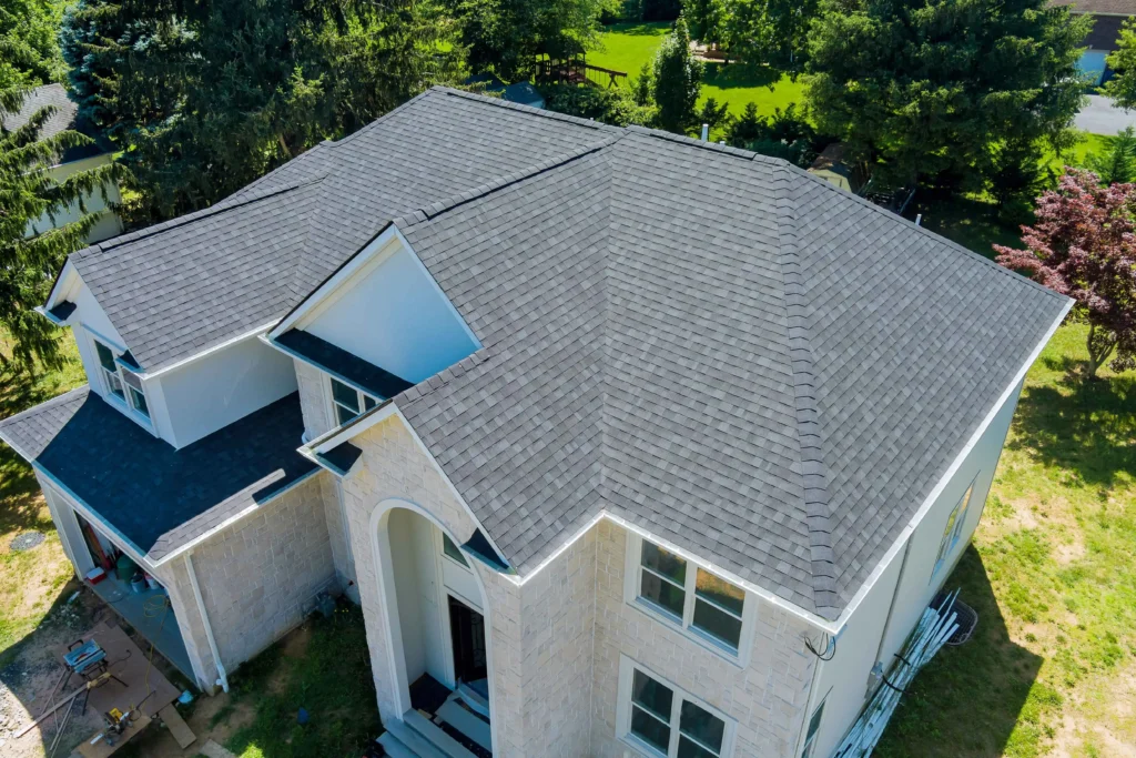 House roofing construction featuring new asphalt shingles and upgraded window, aerial view