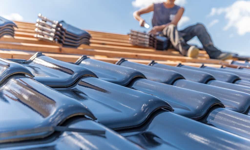 Contractors installing new roof with shingles and protective underlayment