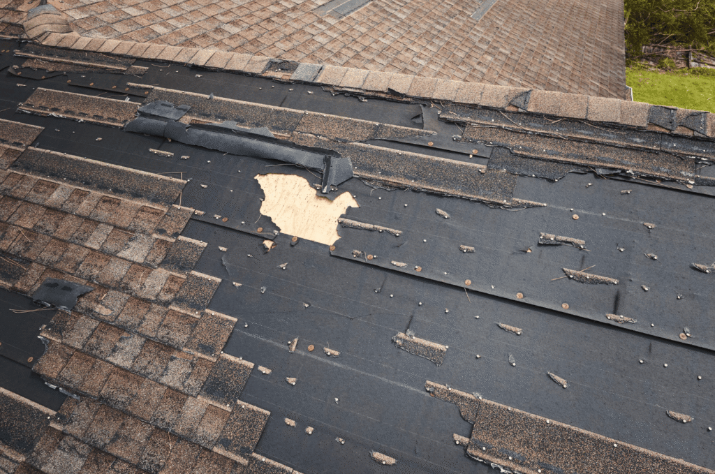 Asphalt shingle roof with missing sections, exposed underlayment, and roof blistering from heat and aging.