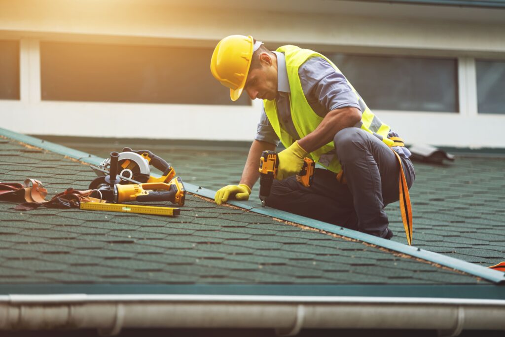 Roofing contractor fixing shingles on roof, performing residential roof repair with safety equipment